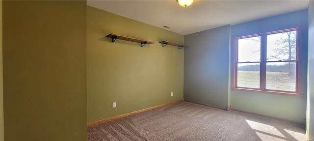 unfurnished room featuring a wealth of natural light, carpet flooring, visible vents, and baseboards