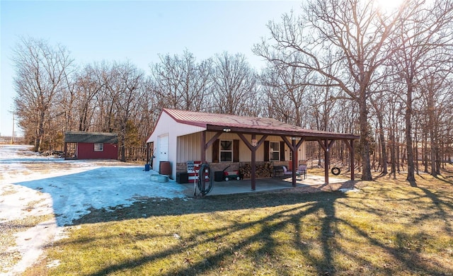 view of front facade featuring a front yard, metal roof, and an outbuilding