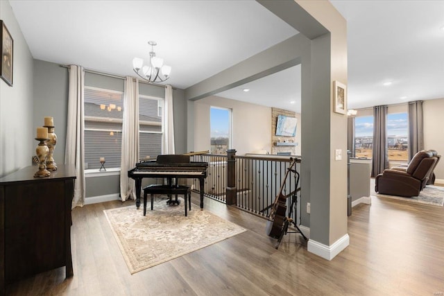 sitting room with baseboards, an upstairs landing, an inviting chandelier, and wood finished floors