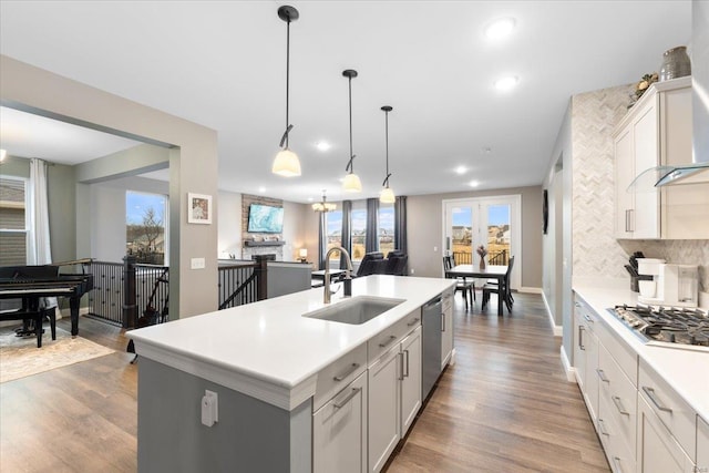 kitchen with a sink, backsplash, appliances with stainless steel finishes, and wood finished floors