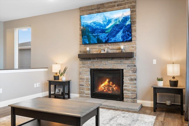 living room with a fireplace, baseboards, and wood finished floors