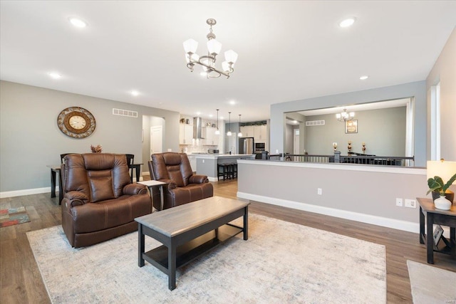 living area with visible vents, baseboards, light wood-type flooring, recessed lighting, and an inviting chandelier