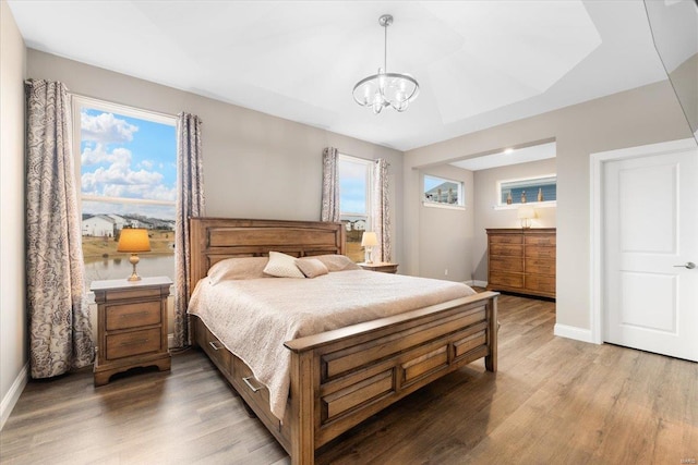 bedroom featuring baseboards, a notable chandelier, and wood finished floors