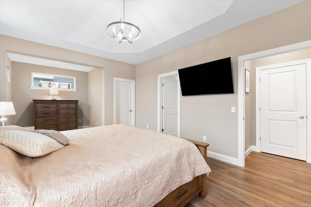 bedroom featuring light wood-type flooring, baseboards, and an inviting chandelier