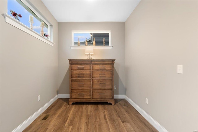 unfurnished bedroom featuring wood finished floors, baseboards, and visible vents