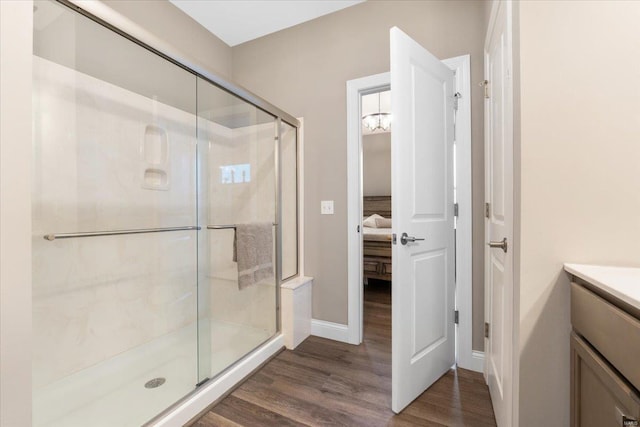 ensuite bathroom featuring vanity, wood finished floors, a stall shower, and ensuite bathroom