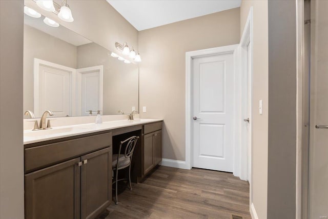 bathroom with double vanity, wood finished floors, baseboards, and a sink