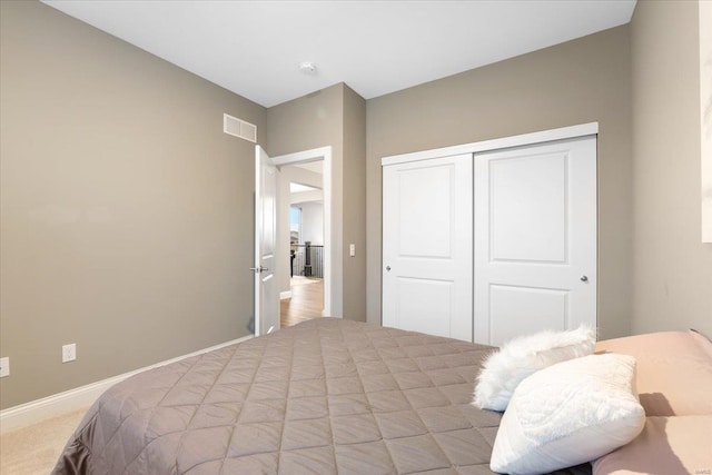 bedroom with a closet, visible vents, carpet flooring, and baseboards