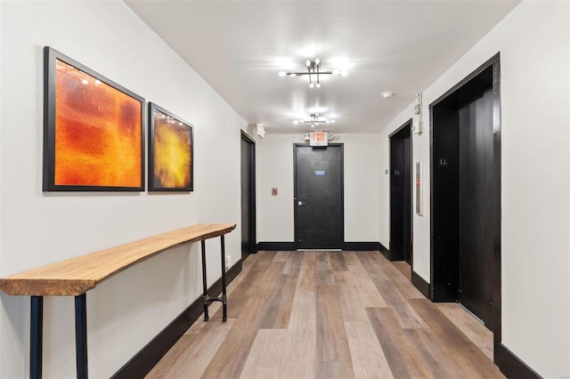 hall with light hardwood / wood-style flooring and elevator