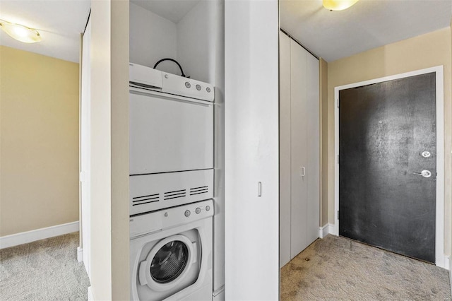 laundry room featuring light colored carpet and stacked washer / dryer