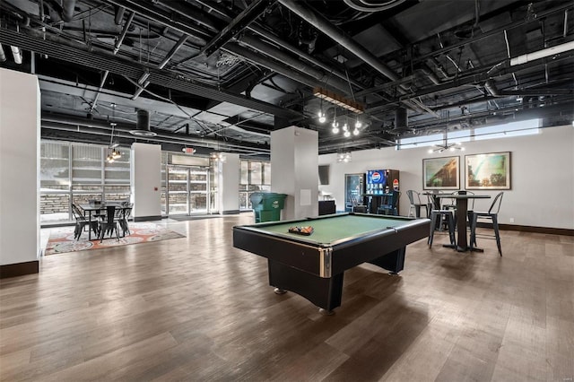 game room featuring hardwood / wood-style floors, pool table, and a towering ceiling