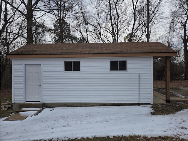 snow covered structure featuring an outbuilding