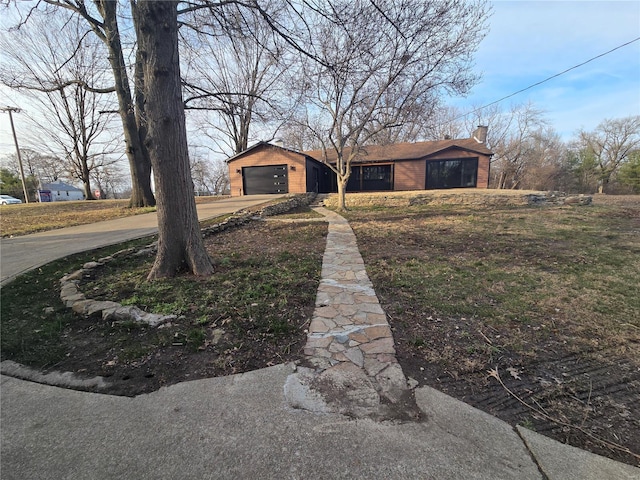 view of front of property with driveway, a chimney, and an attached garage