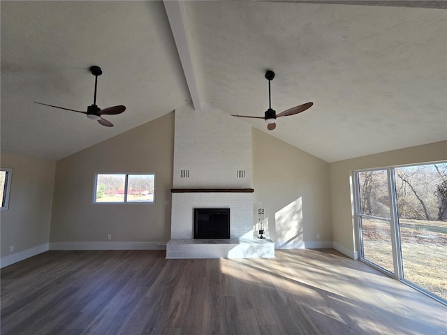 unfurnished living room featuring a brick fireplace, beam ceiling, baseboards, and wood finished floors