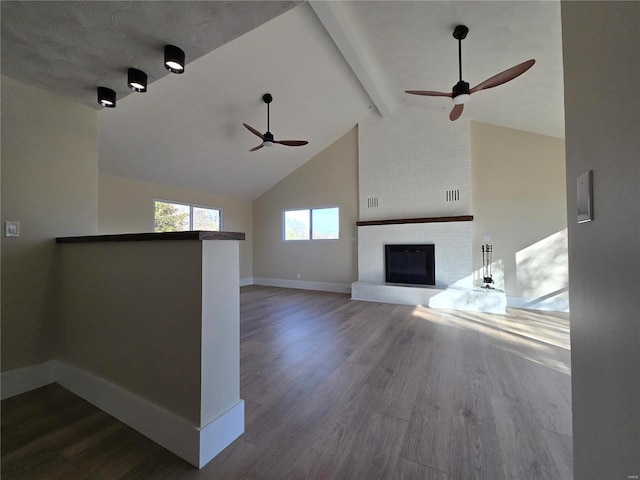 unfurnished living room with beam ceiling, a fireplace, dark wood finished floors, high vaulted ceiling, and baseboards