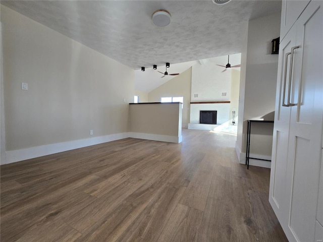 unfurnished room with baseboards, a fireplace, a ceiling fan, and wood finished floors