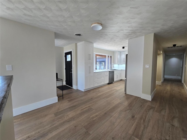 unfurnished living room featuring a textured ceiling, wood finished floors, visible vents, and baseboards