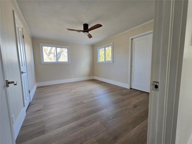 unfurnished bedroom with a ceiling fan, crown molding, baseboards, and wood finished floors