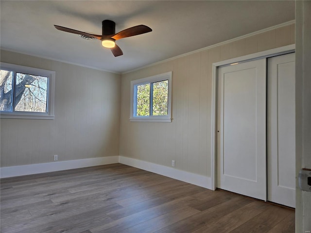 unfurnished bedroom featuring ornamental molding, wood finished floors, and baseboards