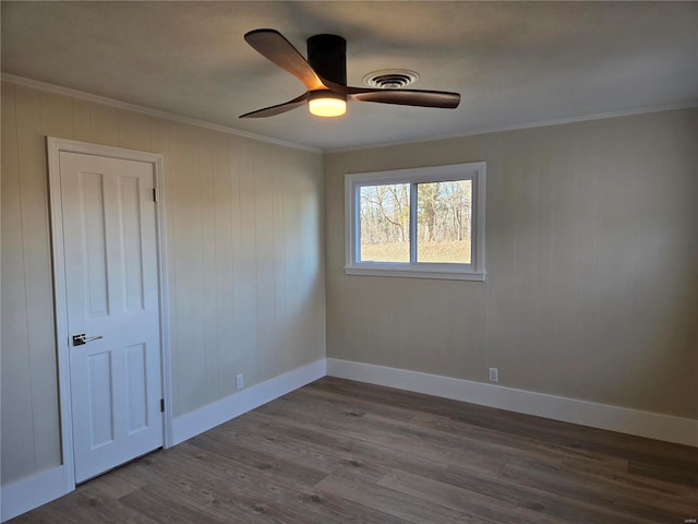 spare room featuring ornamental molding, dark wood-style flooring, visible vents, and baseboards