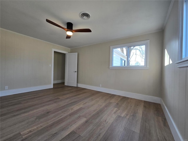 spare room with baseboards, visible vents, ceiling fan, wood finished floors, and crown molding