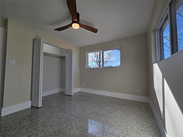 unfurnished bedroom with ceiling fan, baseboards, a closet, and speckled floor