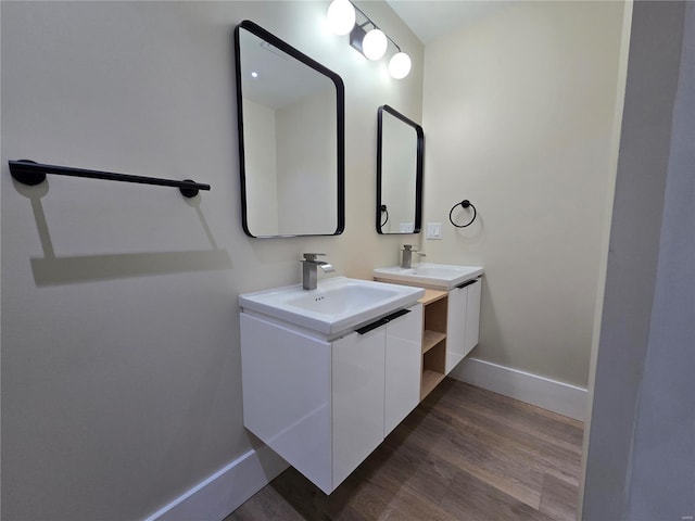 bathroom featuring two vanities, a sink, baseboards, and wood finished floors