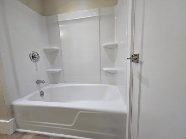 full bath featuring wood finished floors and bathtub / shower combination