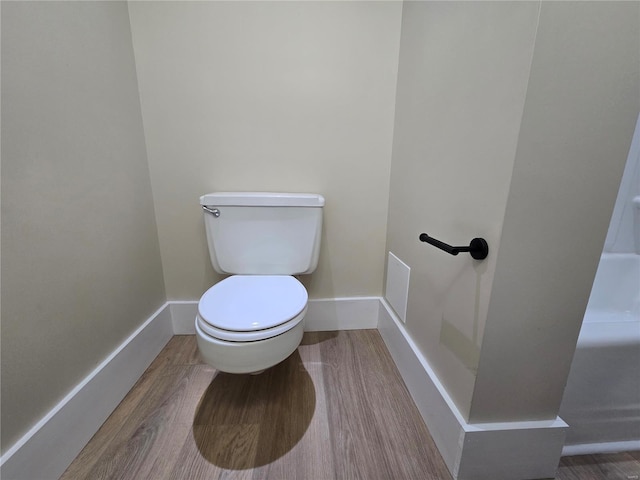 bathroom with wood finished floors, toilet, and baseboards