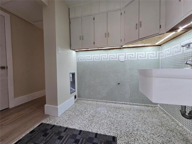 clothes washing area featuring a sink, baseboards, and wood finished floors