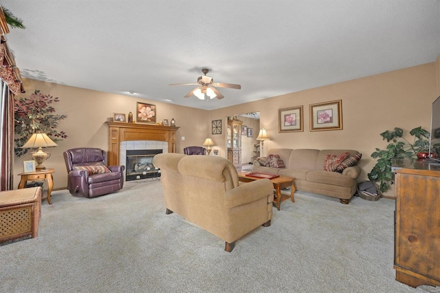 carpeted living room with a tiled fireplace and ceiling fan