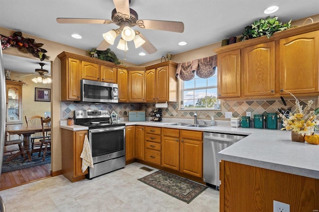 kitchen featuring stainless steel appliances, tasteful backsplash, sink, and ceiling fan