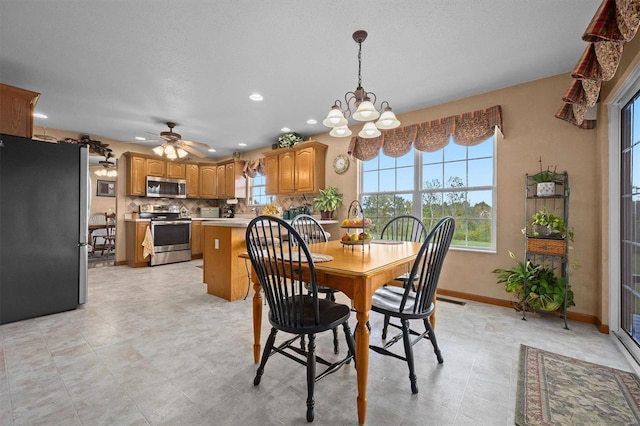 dining area featuring ceiling fan with notable chandelier