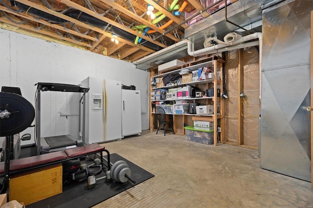 basement with white refrigerator with ice dispenser, heating unit, and white fridge