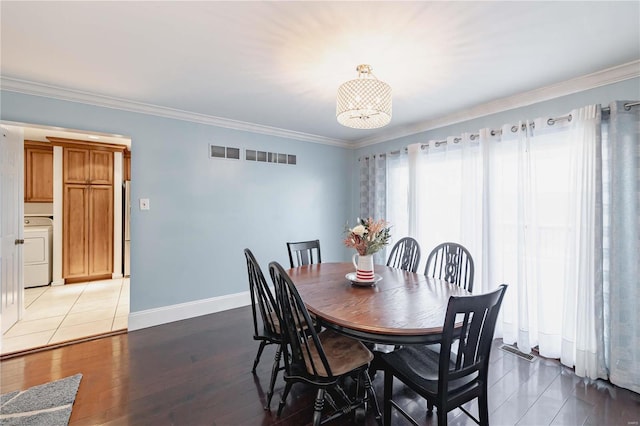 dining area featuring washer / dryer, ornamental molding, and hardwood / wood-style flooring