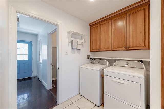 laundry area with washing machine and clothes dryer, cabinets, and light hardwood / wood-style flooring