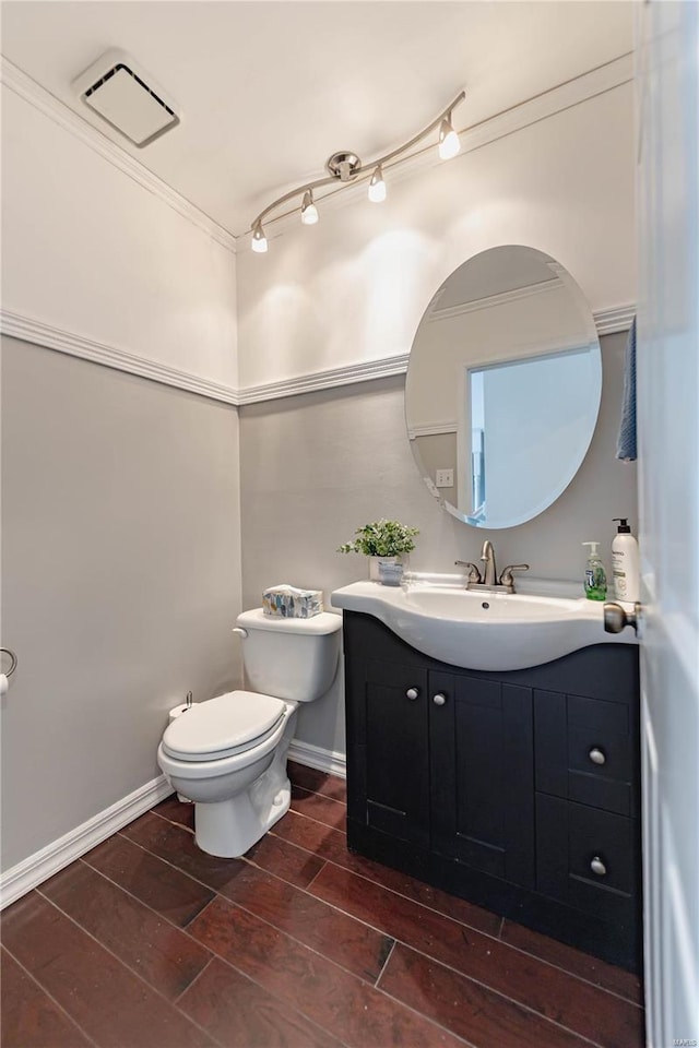 bathroom with toilet, vanity, and crown molding