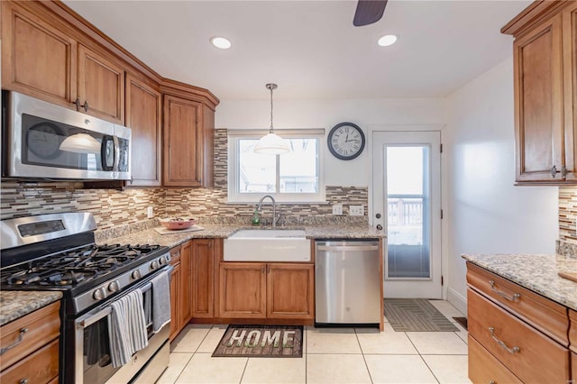 kitchen featuring appliances with stainless steel finishes, light tile patterned floors, light stone counters, sink, and tasteful backsplash