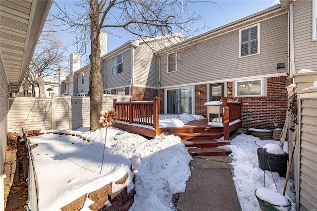 snow covered rear of property with a wooden deck