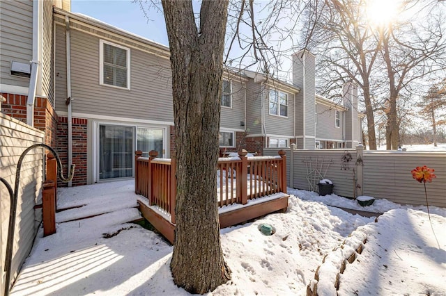 snow covered back of property featuring a wooden deck