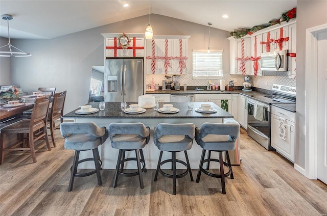 kitchen featuring pendant lighting, a kitchen breakfast bar, a center island, and appliances with stainless steel finishes