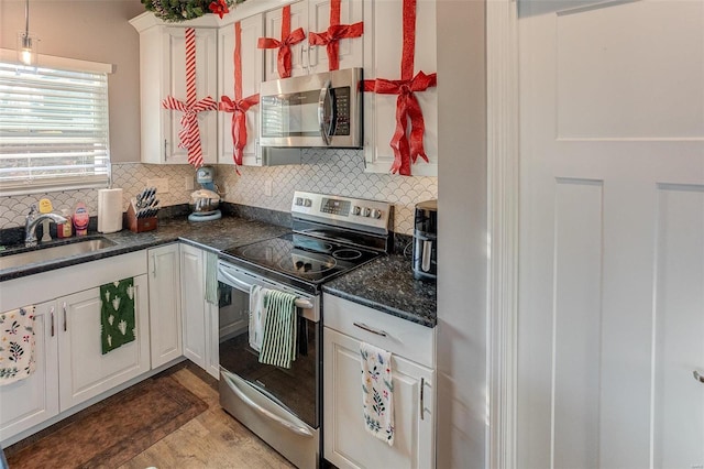 kitchen featuring appliances with stainless steel finishes, tasteful backsplash, white cabinetry, and sink