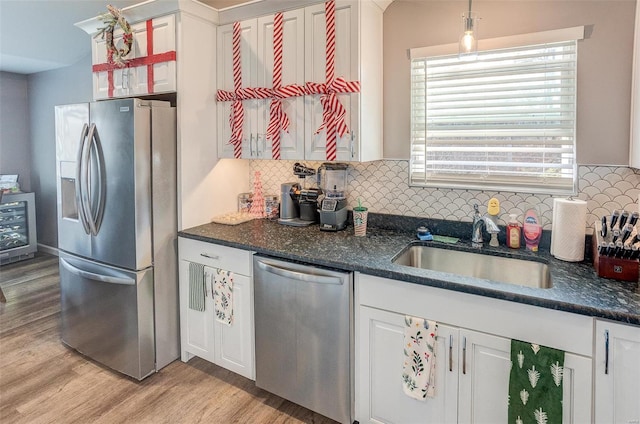 kitchen with white cabinets, backsplash, sink, and stainless steel appliances