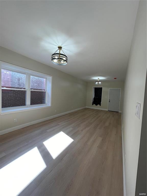 interior space with baseboards, a chandelier, and light wood-style floors