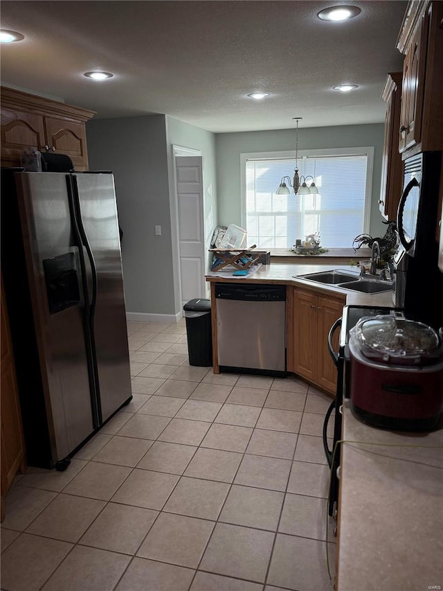 kitchen featuring hanging light fixtures, sink, light tile patterned floors, appliances with stainless steel finishes, and a chandelier