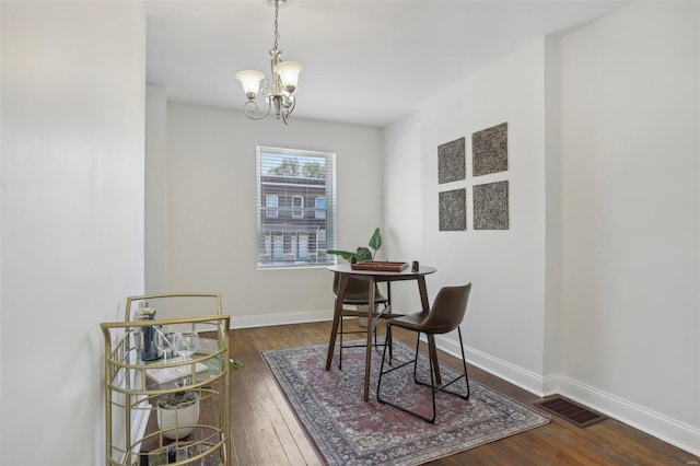 dining area with a chandelier and dark wood-type flooring