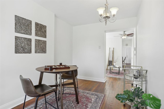 dining room with ceiling fan with notable chandelier and dark hardwood / wood-style floors