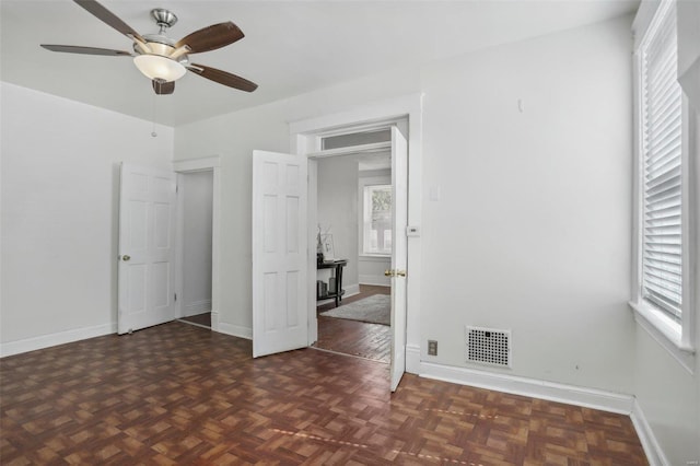 unfurnished bedroom featuring dark parquet flooring and ceiling fan