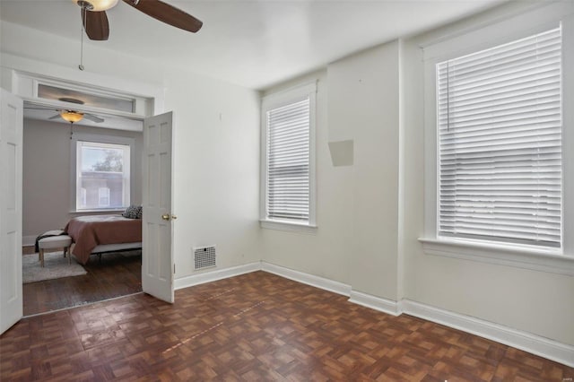 empty room with dark parquet flooring and ceiling fan