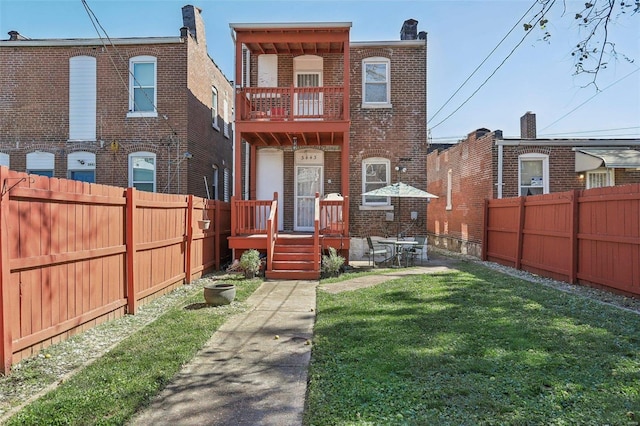 back of house with a balcony and a yard